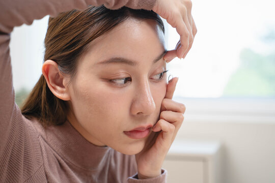 Close-up shot of woman putting contact lens in her eyes