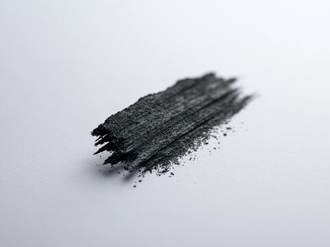 Black charcoal powder smudge on white paper texture