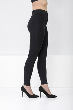 Woman wearing black compression leggings and high heel shoes. Medical hosiery for varicose vein treatment and leg support. Therapeutic garment for healthy circulation and recovery
