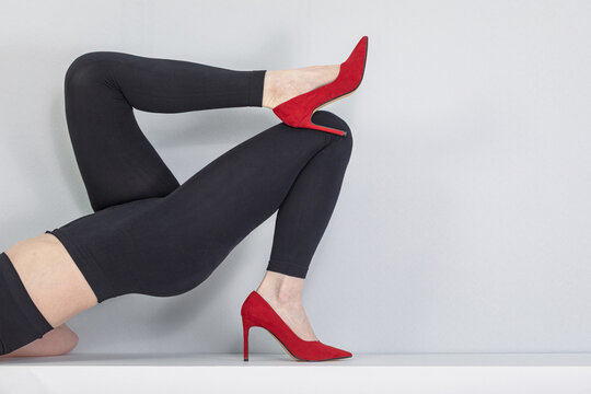Woman wearing black compression leggings and red high heels. Medical hosiery for varicose vein relief and leg fatigue recovery. Fashionable style and health support for tired feet
