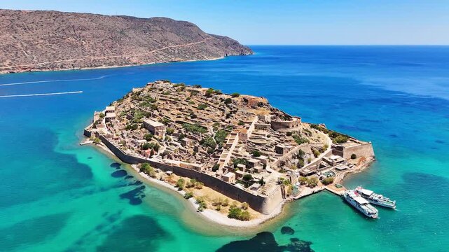 Kalydon Island, historically known as Spinalonga, contains extensive Venetian fortifications, stone ruins and a small harbor surrounded by clear turquoise waters at the entrance to the natural harbor