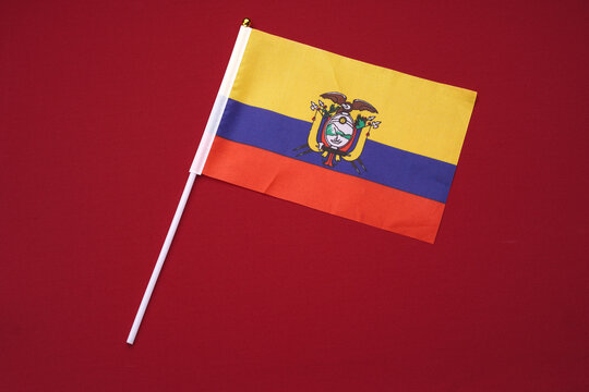 Small flag of Ecuador isolated against a red background.