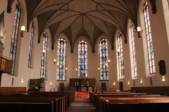 Interior view of a German church with stained glass windows and wooden pews