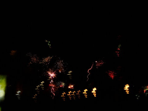 Abstract light trails and fireworks illuminate the dark night sky