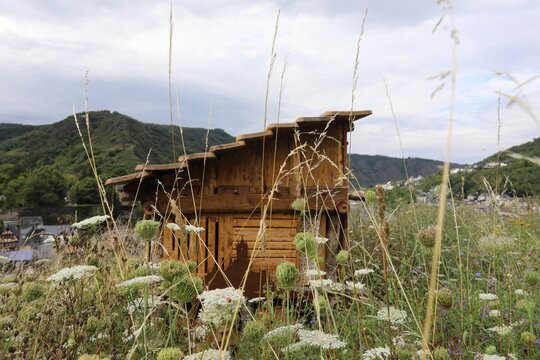 Wooden insect hotel in a meadow with wildflowers and rolling hills
