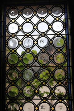 Historic stained glass window with circular panes and green foliage outside