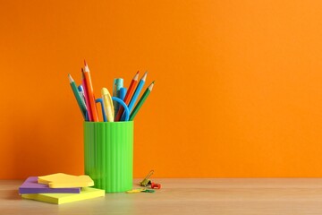 School-themed scene set against orange background with organized stationery and pencil holder, space for text © Sunlight