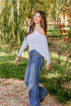 Happy young woman walking under a willow tree