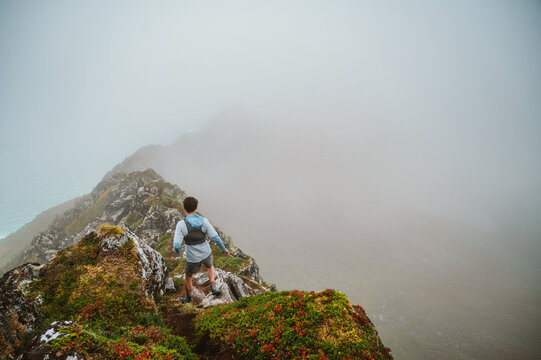 Trail runner stands on a foggy mountain ridge
