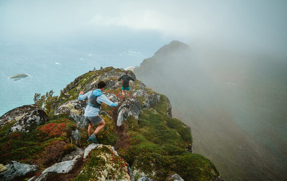 Two men trail running on a foggy mountain ridge by the sea