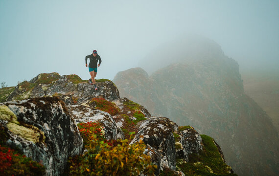 Woman trail running along a foggy mountain crest