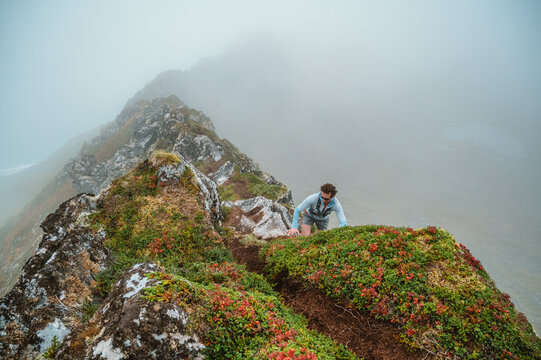 Hiker climbs a narrow and foggy mountain ridge
