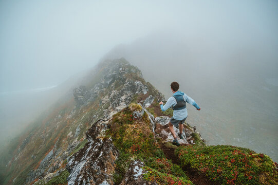 Trail runner descends a foggy alpine ridgeline
