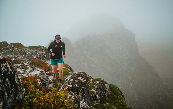 Man trail running along a foggy mountain ridge