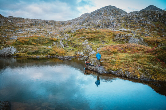 Two hikers pause beside a still mountain lake