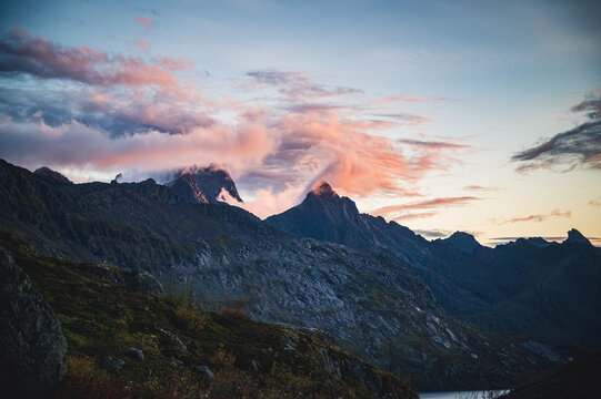 Swirling pink clouds over rugged mountains at twilight
