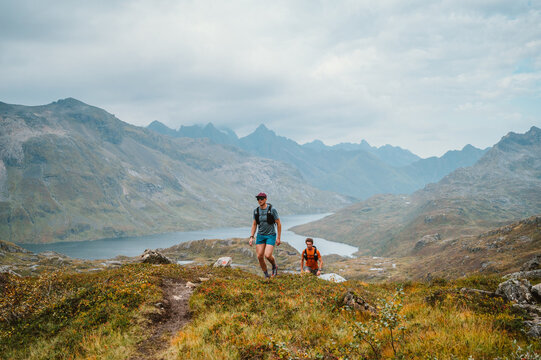 Two men hike a trail in a mountain landscape