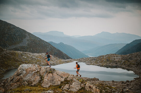 Two friends trail run in a vast mountain landscape