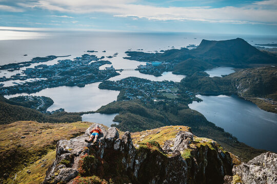 Man resting on a rocky summit above a coastal town