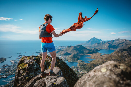 Hiker on mountain summit with wind blowing jacket