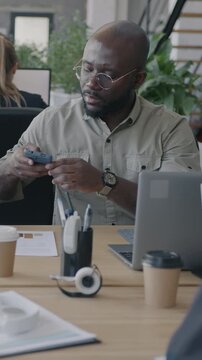 Multiracial group of people employees busy in office making video call with computers and working with documents. Business and workplace concept.