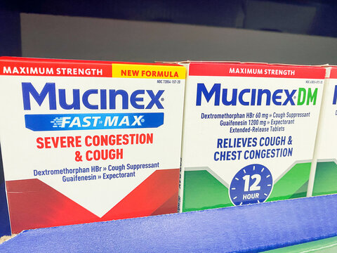 Mucinex Fast-Max and Mucinex DM medicine boxes on a pharmacy retail shelf. - Auburn WA USA - August,21 2026