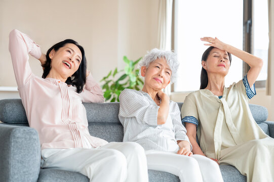  ソファに座り体調不良や疲労に悩む中高年の女性達