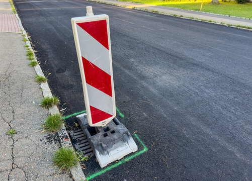 Road Surface Being Resurfaced with Fresh Asphalt &ndash; Road Construction and Infrastructure Repair with traffic sign