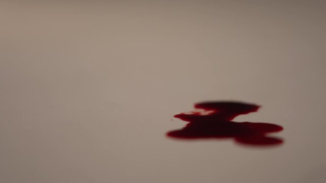 Macro side view zoom in of continuous blood dripping on right side, left copy space, intense dramatic urgency for horror, cinematic close-up for crime scene