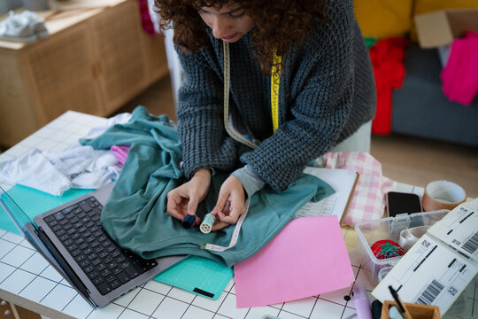 Person sewing button on fabric at creative workspace indoors