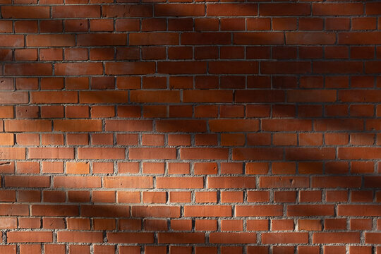 Red brick wall texture with diagonal sunlight and shadows