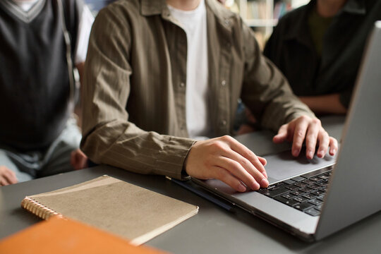 Young man typing on a laptop while studying with a team indoors