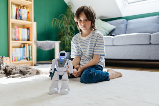 A boy plays with a toy robot using a remote control in a living room