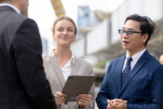 Business teamwork concept. diverse professional colleagues discussing ideas and sharing tablet outdoors in corporate district. teamwork, business, team, collaboration, tablet.