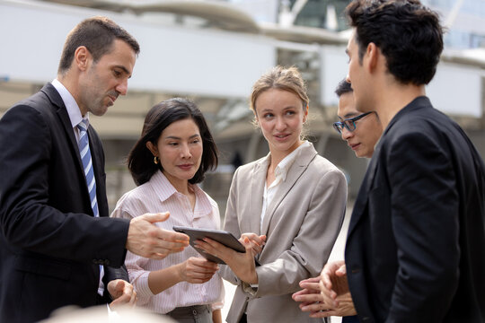 Business teamwork concept. diverse professional colleagues discussing ideas and sharing tablet outdoors in corporate district. teamwork, business, team, collaboration, tablet.