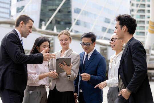 Business teamwork concept. diverse professional colleagues discussing ideas and sharing tablet outdoors in corporate district. teamwork, business, team, collaboration, tablet.