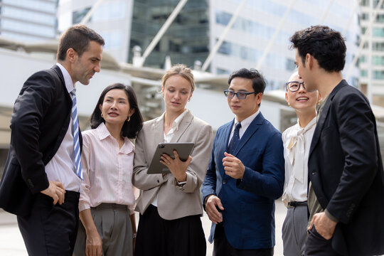 Business teamwork concept. diverse professional colleagues discussing ideas and sharing tablet outdoors in corporate district. teamwork, business, team, collaboration, tablet.