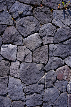 Horizontal view of a rustic dry stone wall texture built with interlocking grey rocks. Photographed in Purwodadi Botanical Garden, Pasuruan, Indonesia on July 4, 2025.