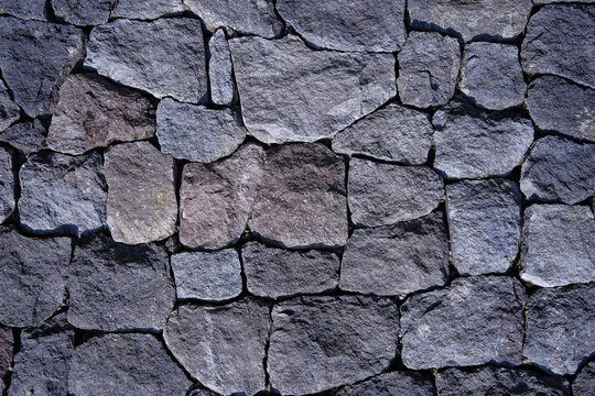 Horizontal view of a rustic dry stone wall texture built with interlocking grey rocks. Photographed in Purwodadi Botanical Garden, Pasuruan, Indonesia on July 4, 2025.