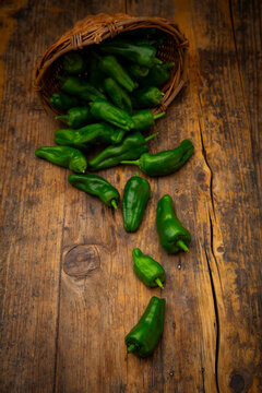 Green Padr�n peppers spill from a woven basket onto dark wood