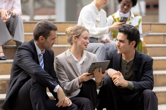 Business teamwork concept, Businessperson brainstorm colleagues discussing ideas and using tablets together while sitting outdoors in corporate setting. teamwork, business, collaboration, tablet.