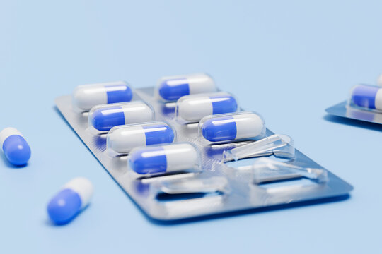 Blue and white medicine capsules rest in a blister pack