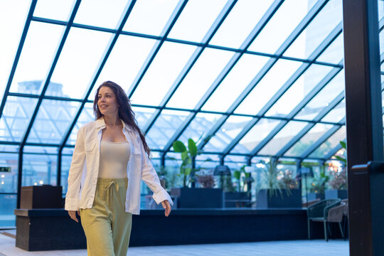 A confident woman walks through a modern glass atrium building