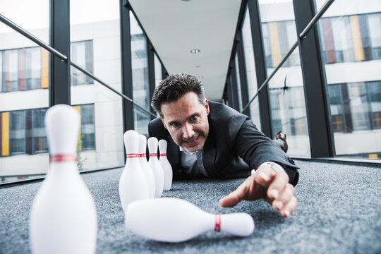 Obsessive manager lying on the floor in office passageway with pins