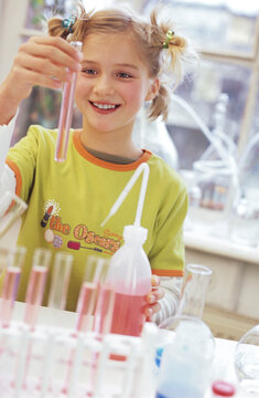 Girl (8-9) holding test tube in chemical lab, smiling