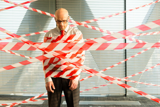 Businessman tangled in barrier tape
