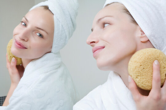 Young woman cleaning her face with a sponge