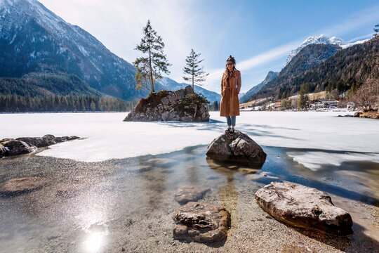 Germany, Bavaria, Ramsau, young woman standing on stone, Hintersee