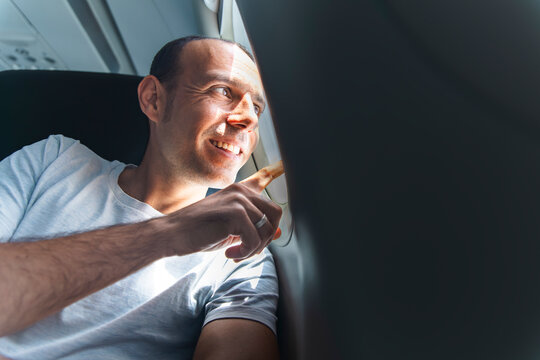 Smiling male passenger points out the airplane window during a flight