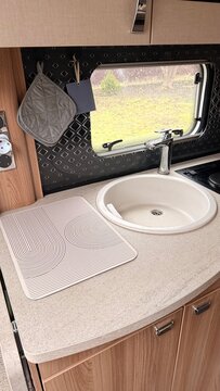 Compact caravan kitchen sink area with modern faucet and wooden countertop inside a camper